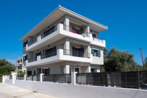 a white apartment building with balconies and a fence at Melina apartments in Lefkada Town