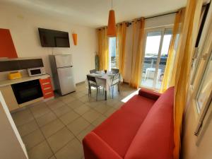a living room with a red couch and a kitchen at Residence El Patio in Lido di Jesolo