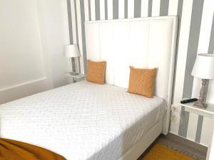 ein weißes Bett mit zwei Kissen und einem Fenster in der Unterkunft Duarte Houses - Casa T1 N - com vista mar in Nazaré