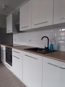 a white kitchen with a sink and white cabinets at Apartament 26 in Drawsko Pomorskie