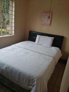 a bed with white sheets and pillows in a bedroom at Naisar's Apartments Primrose,Johannesburg in Johannesburg +49 photos