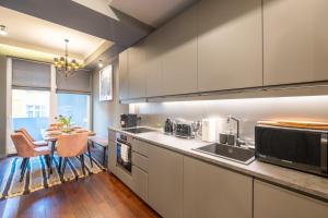 a kitchen with white cabinets and a dining table at Premium Apartments - Top-Notch Place 2BR/2BTH in Sofia