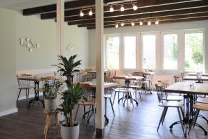 un comedor con mesas, sillas y ventanas en Landhotel Alte Schule - Hotel Garni, en Wangerland