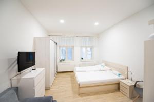 a white room with a bed and a tv at Apartmány Velké náměstí in Kroměříž