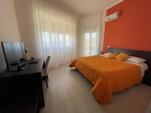 a bedroom with a bed and a desk and a television at Oasis in Acitrezza
