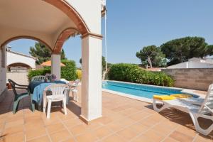 un patio con mesa y sillas junto a una piscina en Tarragona en L'Escala