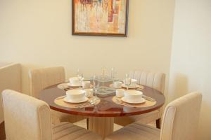 una mesa de comedor con sillas y una mesa de madera con platos. en Apartment en Dubái