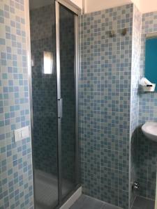 ein Bad mit einer Dusche und blauen Fliesen in der Unterkunft Hotel Centrale in Eraclea Mare
