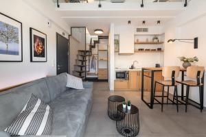 a living room with a gray couch and a kitchen at Cove Suites in Iraklitsa