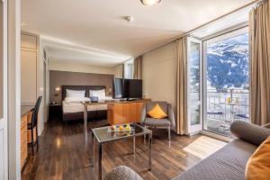 a hotel room with a bed and a couch and a table at Belvedere Swiss Quality Hotel in Grindelwald
