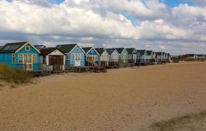 a row of colorful houses on the beach at Stargazing Beach Hut on Mudeford Sandbank with wake up sea views in Christchurch
