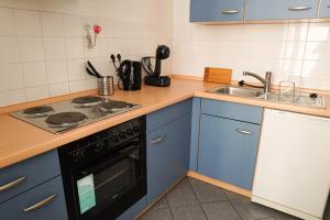 a kitchen with blue cabinets and a stove and a sink at FULL HOUSE Studios - Westside Apartment - Nescafé inkl in Leipzig