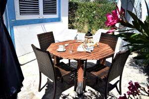a wooden table with chairs and a table with pink flowers at J&D in Dobropoljana