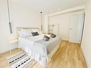 a white bedroom with a large bed and wooden floors at Casa Natura Elx in Elche