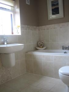 a bathroom with a sink and a tub and a toilet at Ladderstile Retreat in Congleton