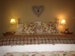 een bed met twee kussens en een hart aan de muur bij Ladderstile Retreat in Congleton