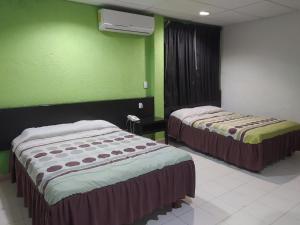 two beds in a room with green walls at Hotel y Restaurante Ritz de Tabasco in Villahermosa