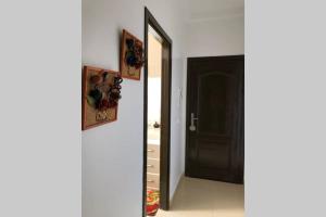 a hallway with a black door and two pictures at Joli Appartement Propre et Équipé: Jardins d'Ifran in Ifrane