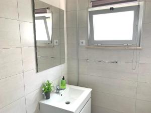 uma casa de banho branca com um lavatório e um espelho em Duarte Houses - Casa T1 N - com vista mar na Nazaré