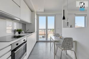 cocina con armarios blancos, mesa y sillas en MS Apartments Green Hill I, en Gdynia