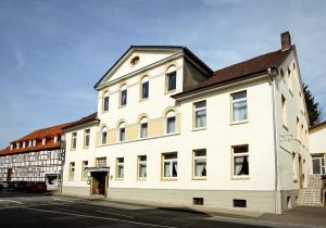 ein weißes Gebäude mit einer Uhr auf dem Dach in der Unterkunft Ackfeld Hotel-Restaurant in Büren