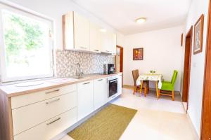 a kitchen with white cabinets and a table with green chairs at Apartment Stanka in Novalja