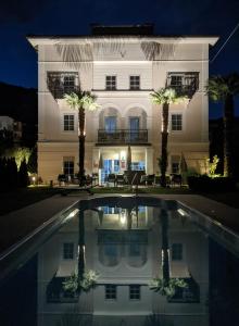 a large white building with palm trees in front of a pool at Garni Villa Tyrol - Adults Only in Merano