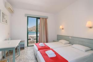 a hotel room with two beds and a desk and a table at Anthi Maria Beach Apartments in Pefki