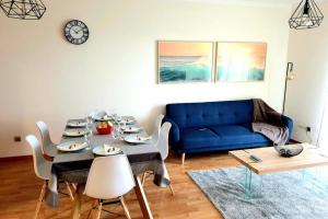 a living room with a table and a blue couch at Hill & Sea House in Ribeira Grande
