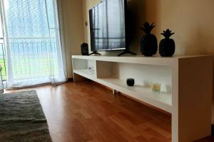 a living room with a television on a white shelf at Hill & Sea House in Ribeira Grande