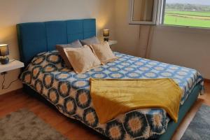a bedroom with a blue bed with pillows and a window at Hill & Sea House in Ribeira Grande