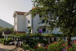a white building with cars parked in a parking lot at Renome in Petrovac na Moru