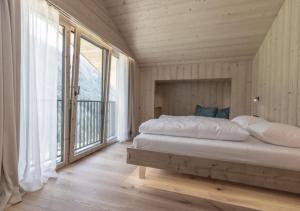 a bedroom with a bed and a large window at Chalet Tschogerhof Tiers am Rosengarten Dolomiten in Tires