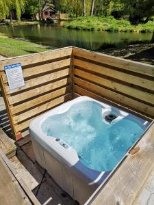 une baignoire jacuzzi assise sur une terrasse à côté d'une rivière dans l'établissement Otter 1 HuntersMoon-Warminster-Longleat-Wiltshire, à Warminster