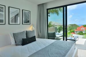 ein Schlafzimmer mit einem großen Bett und einem großen Fenster in der Unterkunft Rêve de Saint Barth - Vue Mer - Piscine Chauffée & Jacuzzi in Gustavia