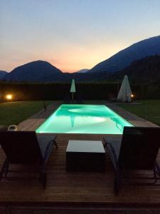 una piscina con 2 sillas y una puesta de sol en LA TANA DEL GRILLO, en Feltre