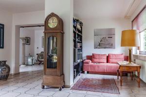 uma sala de estar com um relógio avô e um sofá rosa em Top-bewertete Komfort-Ferienwohnung mit Sonnenterrasse und Garten in der Lüneburger Heide em Hanstedt