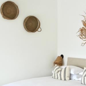 a bedroom with white walls and rattan baskets on the wall at Harbour View House in St Ives