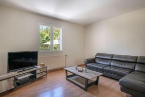 a living room with a leather couch and a television at Vacances détente dans cette maison avec piscine à Crac'h in Crach
