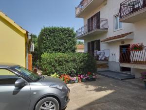 a car parked in front of a house with flowers at Apartmani Danica in Biograd na Moru