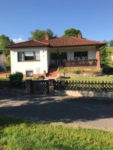 ein weißes Haus mit einem Zaun davor in der Unterkunft Ferienhaus Anita am Radweg in Hornbach