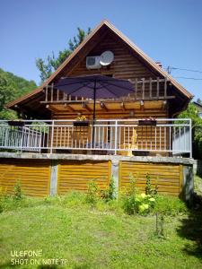 une maison avec un balcon et un parasol dans l'établissement Apartman Relax in Nature, à Jajce
