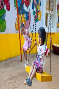 two children playing on swings in a playground at Adamo The Bellus in Calangute