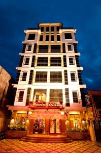 a tall white building with a restaurant in front of it at Hotel Maximillian in Tanjung Balai Karimun