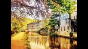 a view of a river with buildings on the side at 4 bedroom period Townhouse in the heart of Hebden in Hebden Bridge
