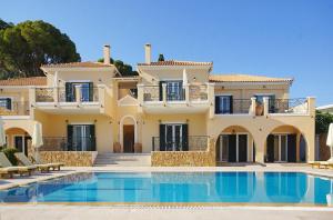 a large villa with a swimming pool in front of it at Aegean Villas in Poros
