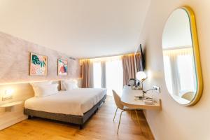 um quarto de hotel com uma cama, uma secretária e um espelho em Ilot du Golf BW Premier Collection em Mandelieu-la-Napoule