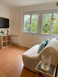 uma sala de estar com um sofá branco e duas janelas em LE COSY - Lumineux - Proche de Rennes - Spacieux em Liffré