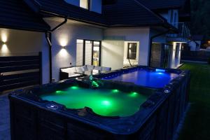 a hot tub in the backyard of a house at night at DOMINO-APARTAMENTY Blue in Krościenko