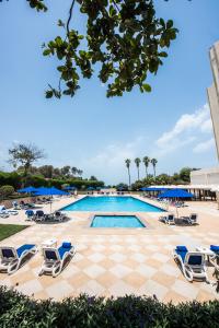 a pool with lounge chairs and a checkered floor at BM Beach Hotel in Ras al Khaimah